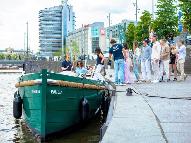 Passagiere steigen in ein grünes Grachtenboot von Eco Boats ein